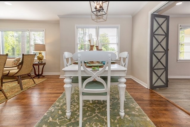 dining room with an inviting chandelier, crown molding, and dark wood-type flooring