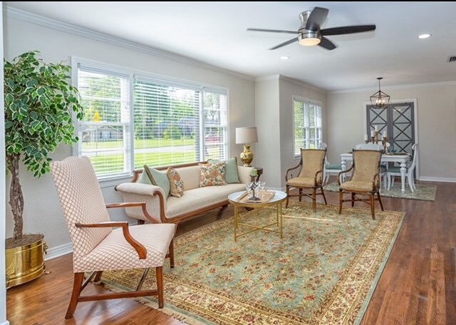 interior space with a wealth of natural light, crown molding, ceiling fan, and dark wood-type flooring