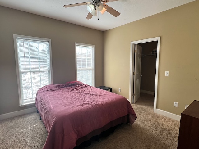 bedroom with a closet, a walk in closet, light colored carpet, and ceiling fan