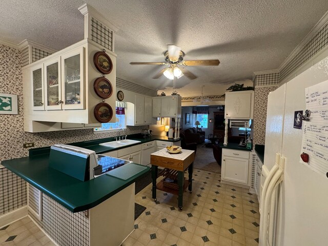 1001 Hall St, Bainbridge, GA 39819 - kitchen with a peninsula, a textured ceiling, dark countertops, wallpapered walls, and a ceiling fan