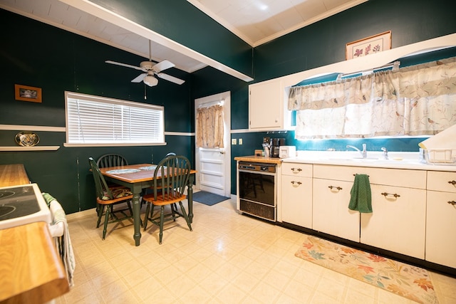 kitchen with ceiling fan, crown molding, light countertops, a sink, and electric stove