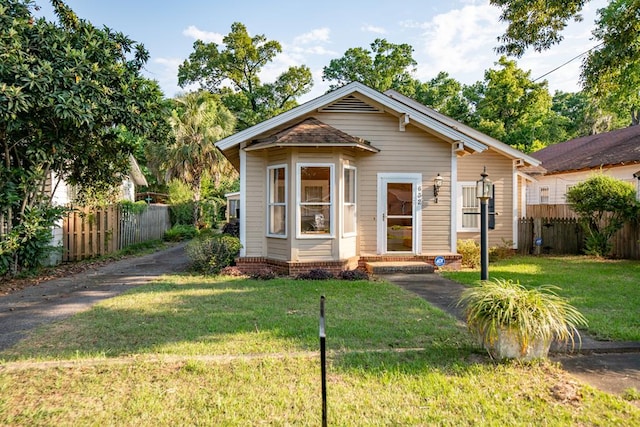 bungalow-style home with fence and a front yard
