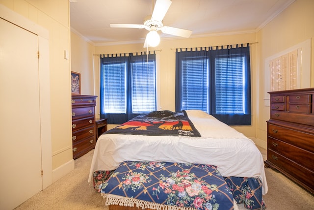 carpeted bedroom with ornamental molding and a ceiling fan
