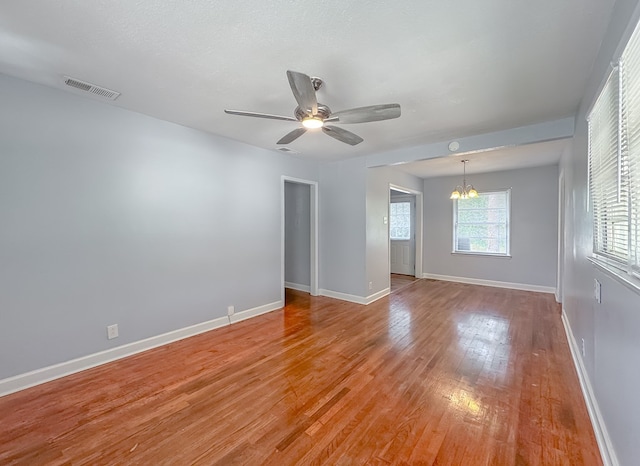 unfurnished room featuring a textured ceiling, ceiling fan with notable chandelier, and light hardwood / wood-style flooring