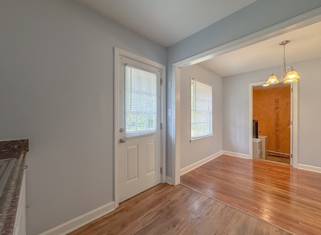 doorway featuring light wood-type flooring and a chandelier