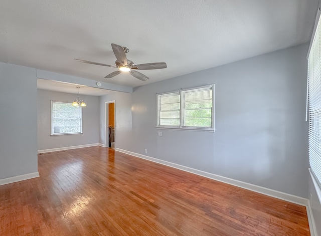 unfurnished room with ceiling fan with notable chandelier and wood-type flooring