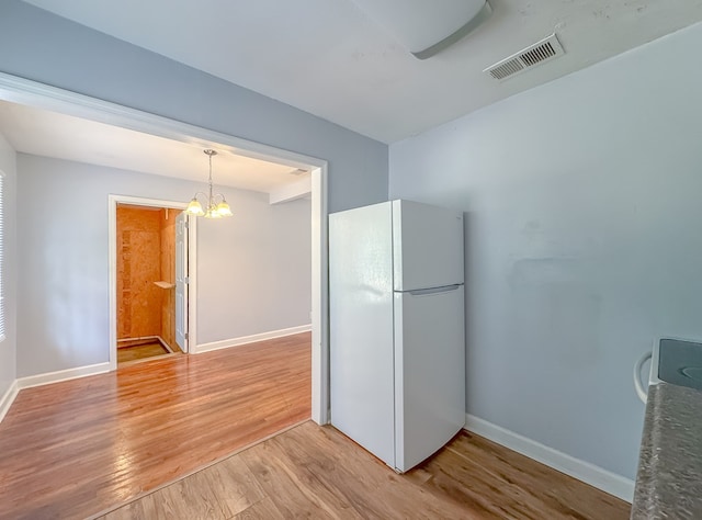 kitchen featuring ceiling fan with notable chandelier, white fridge, hanging light fixtures, and hardwood / wood-style floors