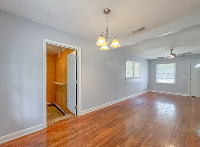 empty room with ceiling fan with notable chandelier and hardwood / wood-style flooring