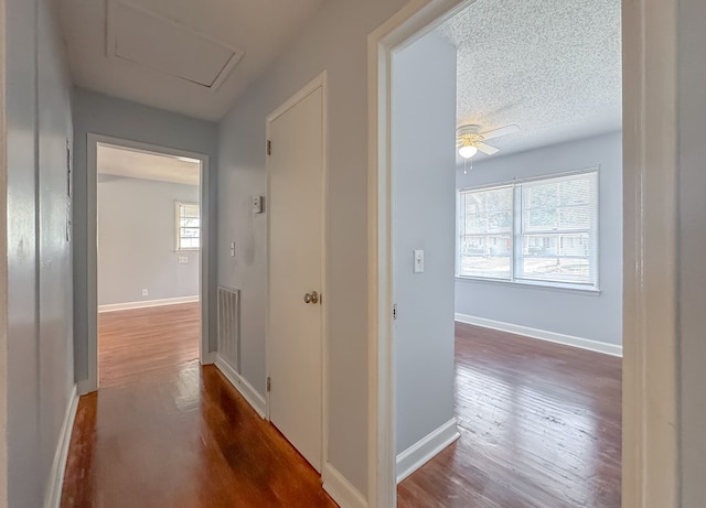 corridor with a textured ceiling and dark hardwood / wood-style floors