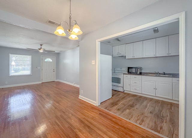 kitchen with white cabinets, white range with electric stovetop, hanging light fixtures, and sink