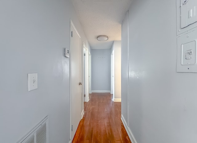 corridor with hardwood / wood-style floors and a textured ceiling