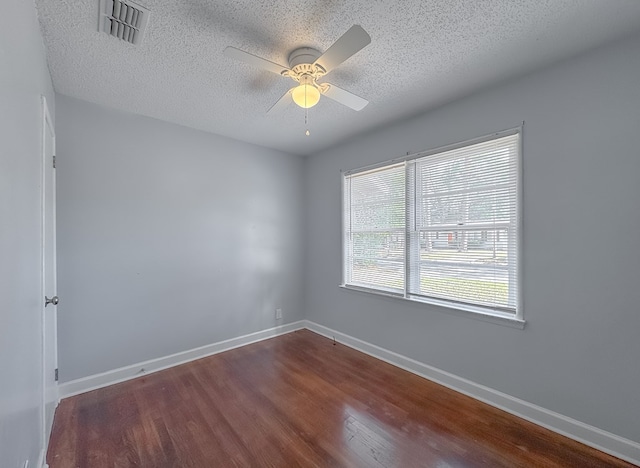 empty room with ceiling fan, dark wood-type flooring, and a textured ceiling