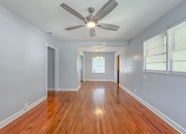 spare room with ceiling fan with notable chandelier and light hardwood / wood-style flooring