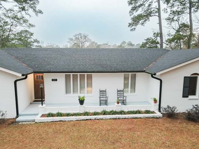 back of house with covered porch and a lawn