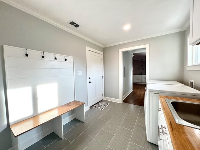 mudroom featuring ornamental molding, sink, and independent washer and dryer