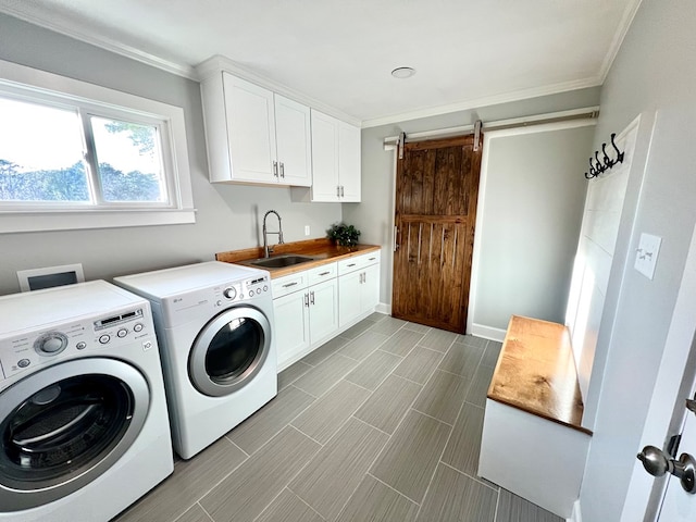 laundry area featuring sink, crown molding, cabinets, washing machine and clothes dryer, and a barn door