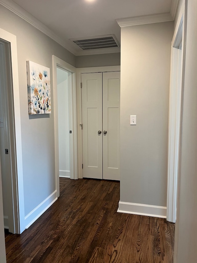 hallway with dark wood-type flooring and ornamental molding