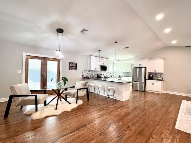 dining space featuring dark hardwood / wood-style flooring, vaulted ceiling, and french doors