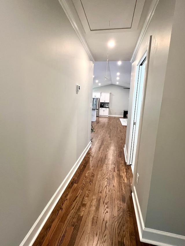 corridor featuring ornamental molding, wood-type flooring, and vaulted ceiling