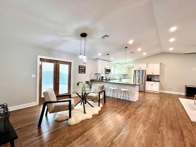 dining room with vaulted ceiling, hardwood / wood-style floors, and french doors