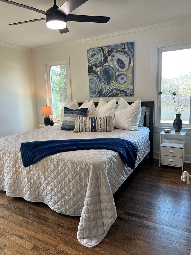 bedroom with ornamental molding, dark wood-type flooring, and ceiling fan