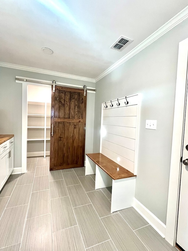 mudroom with crown molding and a barn door