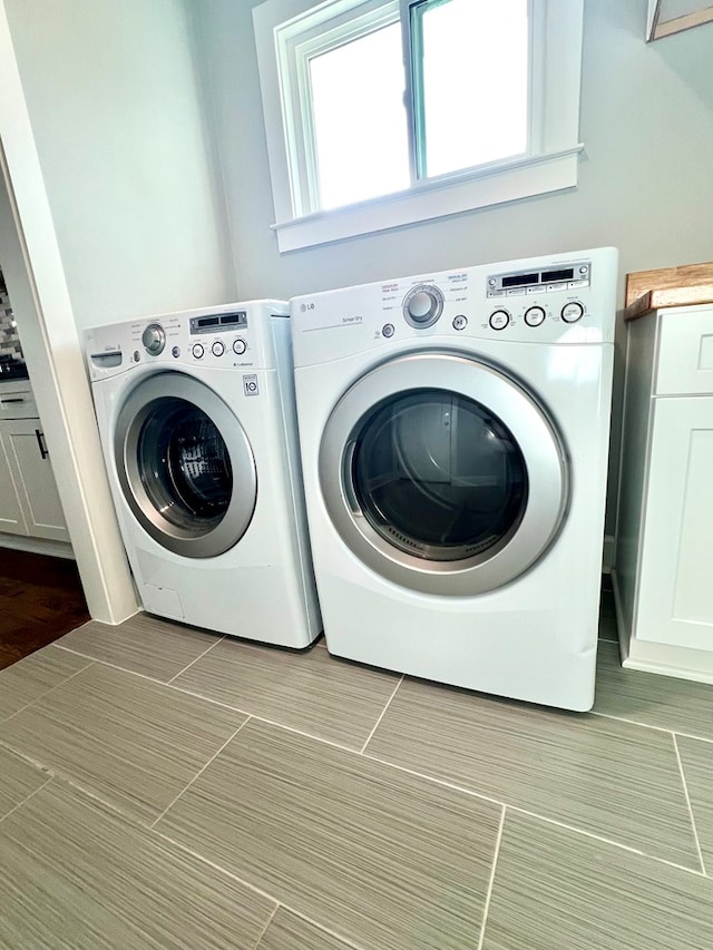 laundry area with washer and clothes dryer and cabinets