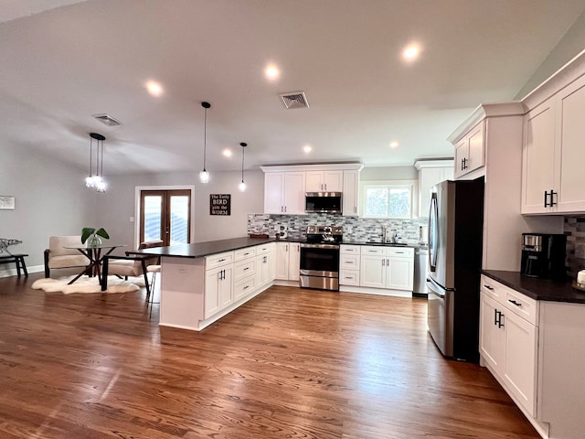 kitchen with white cabinetry, kitchen peninsula, pendant lighting, stainless steel appliances, and backsplash