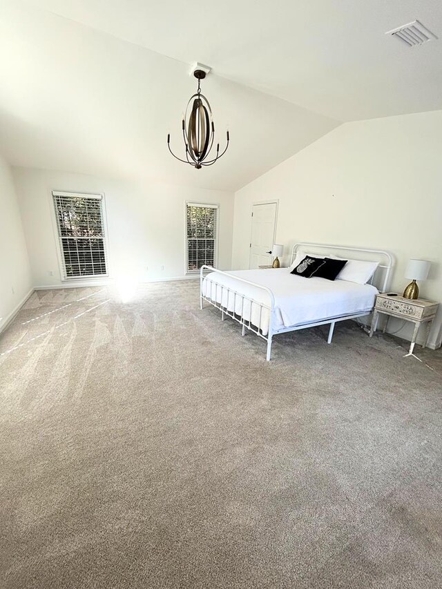 carpeted bedroom featuring lofted ceiling and a chandelier