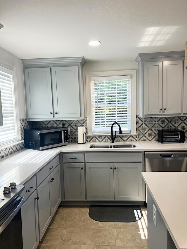 kitchen with gray cabinetry, sink, decorative backsplash, and appliances with stainless steel finishes