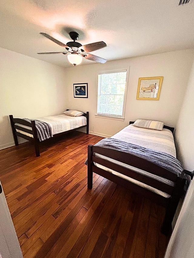 bedroom with dark hardwood / wood-style floors and ceiling fan