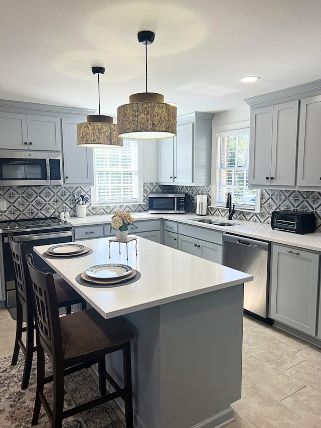 kitchen featuring stainless steel appliances, a center island, sink, and pendant lighting