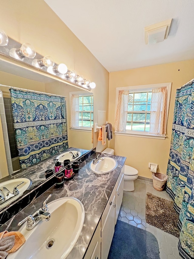 bathroom with tile patterned floors, plenty of natural light, toilet, and vanity