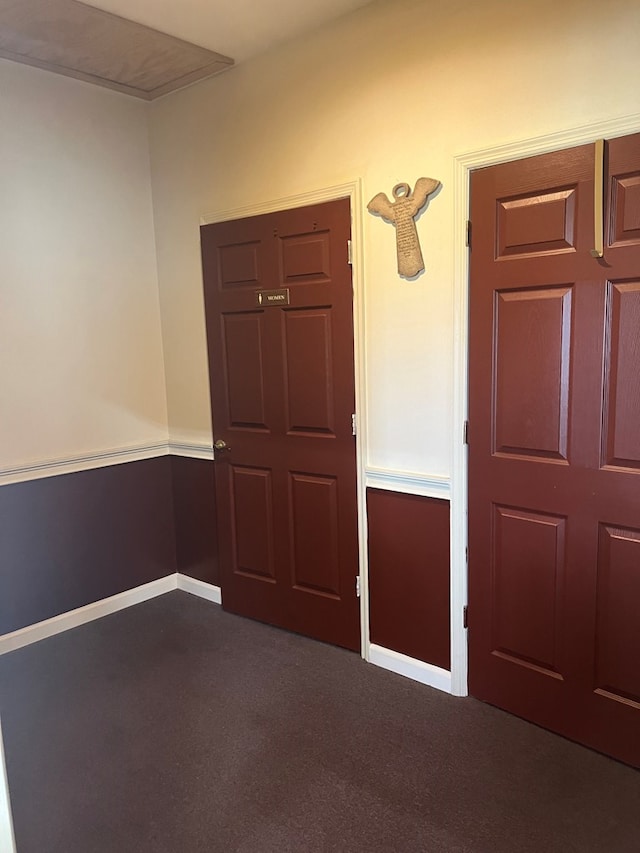 foyer entrance featuring dark carpet and baseboards