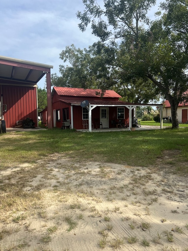 rear view of house with board and batten siding, metal roof, and a lawn