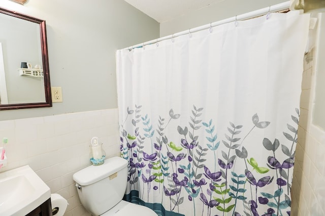 bathroom with a textured ceiling, vanity, tile walls, and toilet
