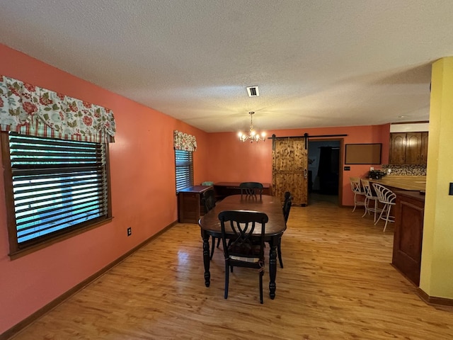 145 Robin Ln, Bainbridge, GA 39819 - dining room featuring a barn door, light wood-style flooring, a textured ceiling, and a chandelier