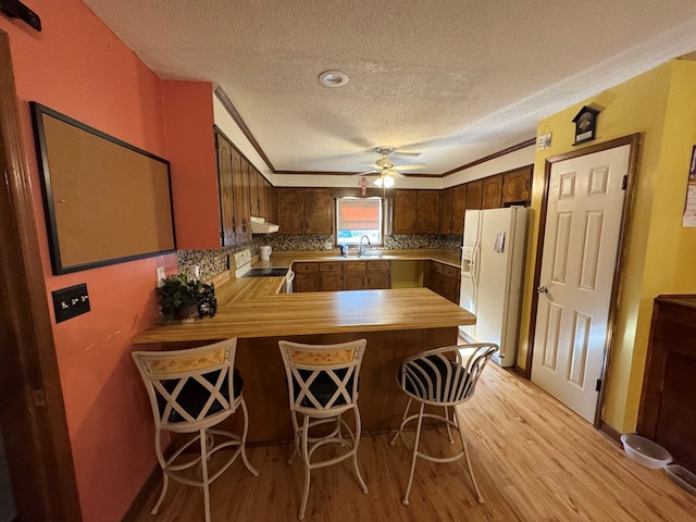 145 Robin Ln, Bainbridge, GA 39819 - kitchen with white appliances, a textured ceiling, light wood-type flooring, range hood, and a peninsula