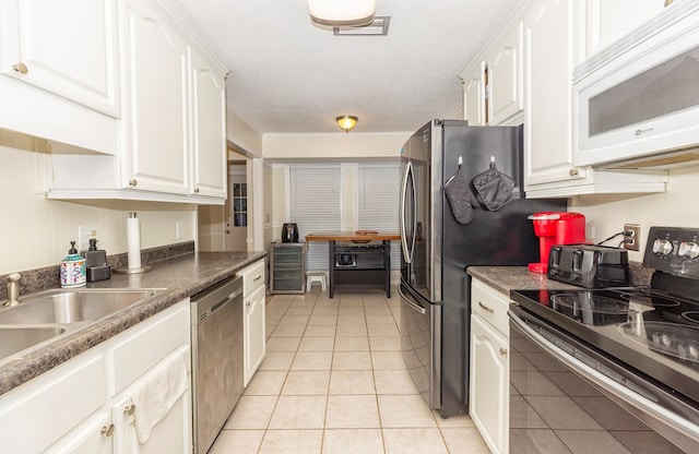 1107 Douglas Dr, Bainbridge, GA 39819 - kitchen featuring stainless steel appliances, white cabinetry, light tile patterned flooring, a sink, and a textured ceiling