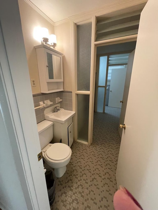 bathroom featuring toilet, ornamental molding, sink, and tasteful backsplash