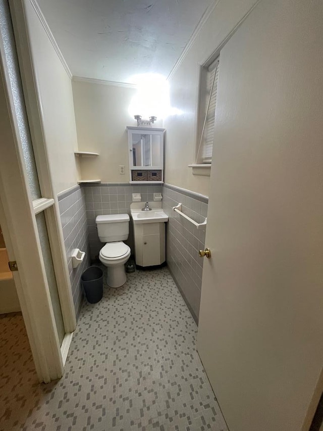 bathroom with vanity, toilet, tile walls, and ornamental molding