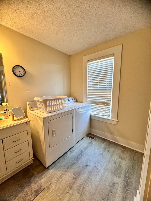 laundry area with light hardwood / wood-style floors, independent washer and dryer, and a textured ceiling