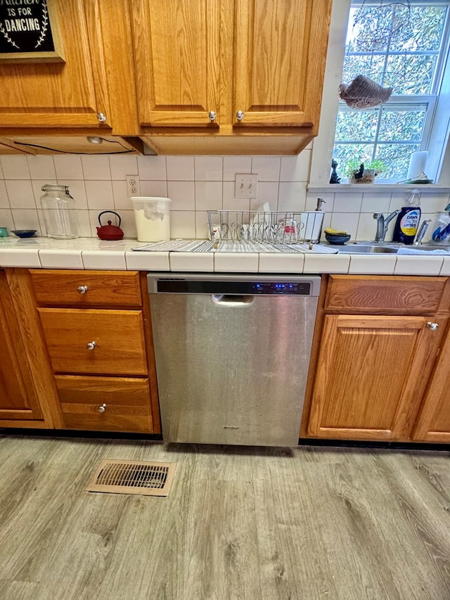 kitchen with dishwasher, backsplash, light hardwood / wood-style floors, and sink