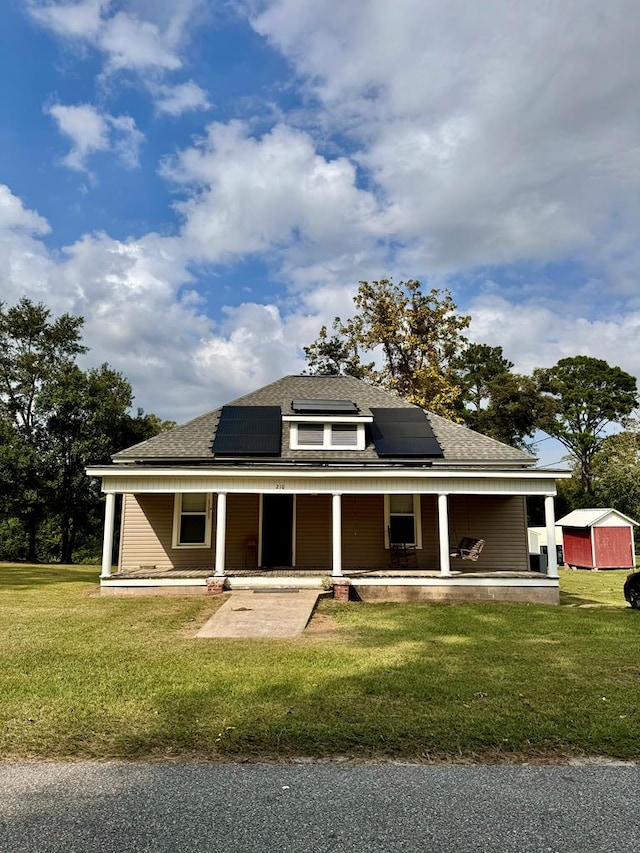 back of property with a lawn, a storage shed, a porch, and solar panels