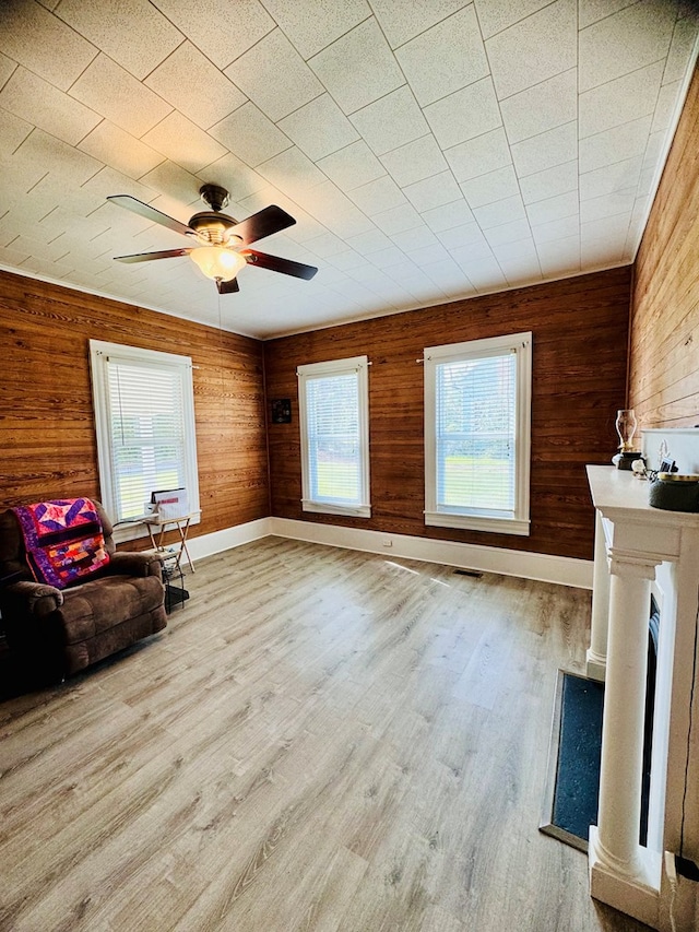 unfurnished room featuring wood walls, ceiling fan, and light wood-type flooring