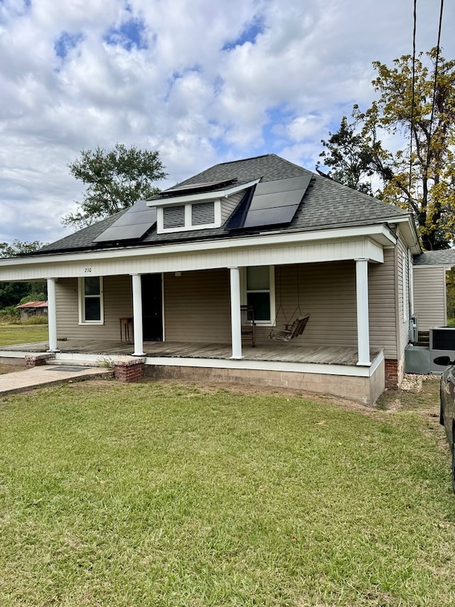 view of front of property with solar panels, covered porch, and a front lawn