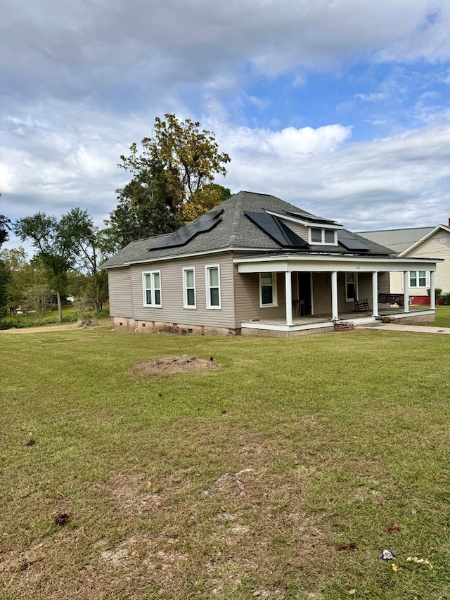 back of property featuring a lawn, a patio, covered porch, and solar panels