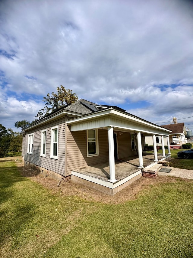 view of side of home featuring a lawn and a porch