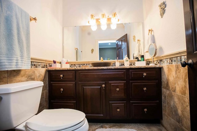 bathroom with vanity, toilet, and tile walls