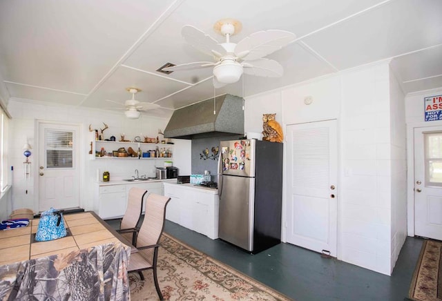 kitchen featuring white cabinets, wall chimney exhaust hood, stainless steel fridge, and sink